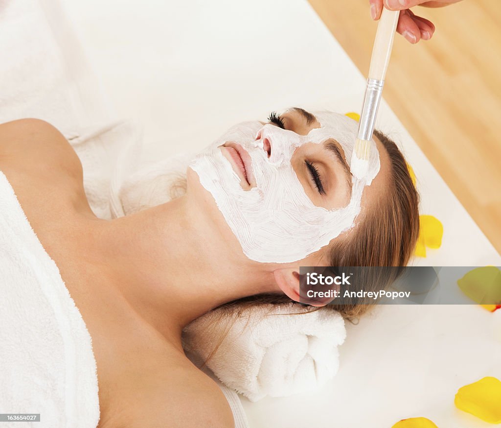 Therapist applying a face mask Therapist applying a face mask to the face of a beautiful young blonde woman using a cosmetic brush Peel - Plant Part Stock Photo