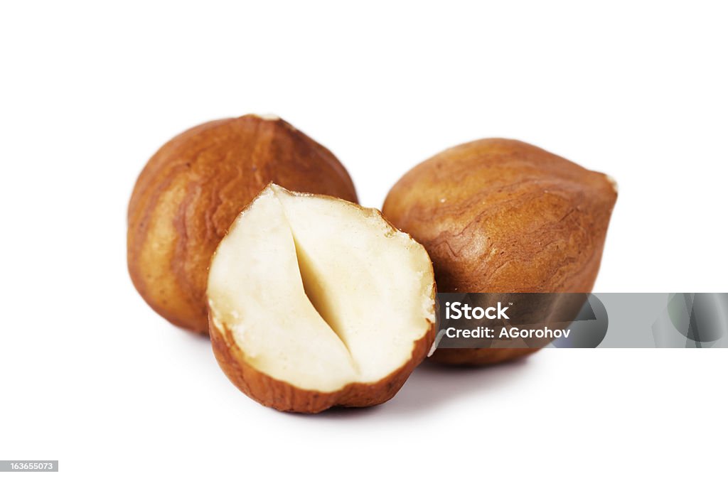 2 whole hazelnuts and 1 half hazelnut on a white background Closeup view of hazelnuts over white background Hazelnut Stock Photo