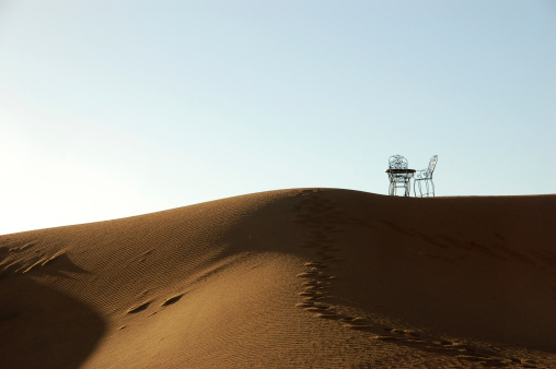 Wrought iron table and chairs on the top of sand dune of Erg Chebbi in the Sahara Desert, Morocco