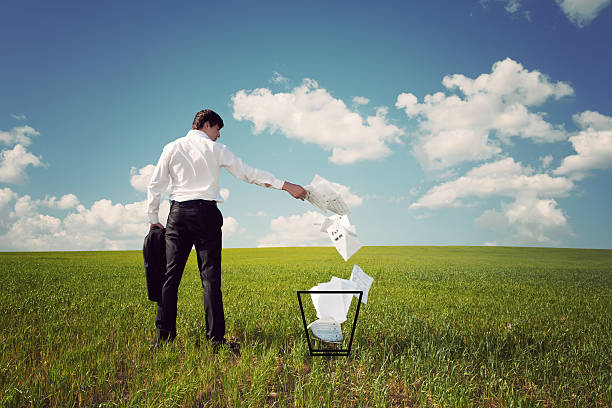 istock businessman a green field throws papers in the trash 163661220