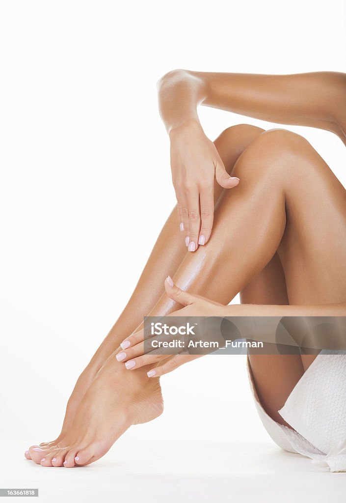 Female legs Applying moisturizer cream on the legs  isolated on white background Adult Stock Photo