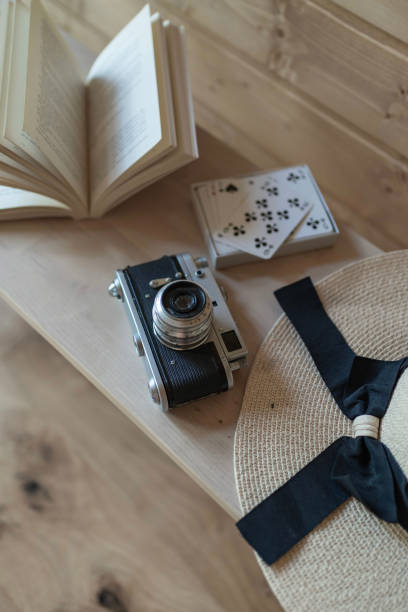 książka, aparat fotograficzny, karty i kapelusz przeciwsłoneczny na drewnianej podłodze - home interior luxury book chalet zdjęcia i obrazy z banku zdjęć