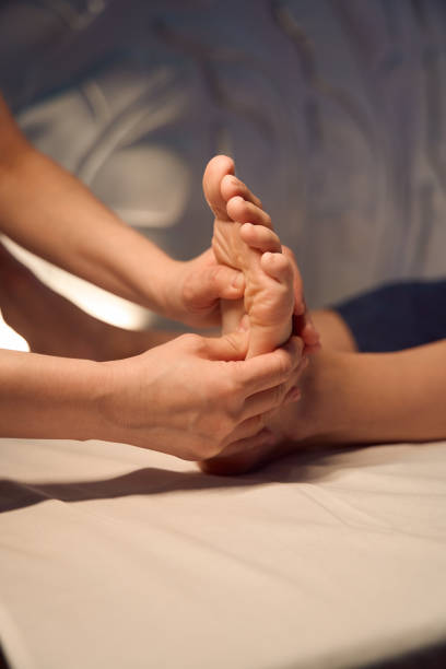 experienced masseuse massaging client foot with hands - reflexology massaging recovery sport imagens e fotografias de stock