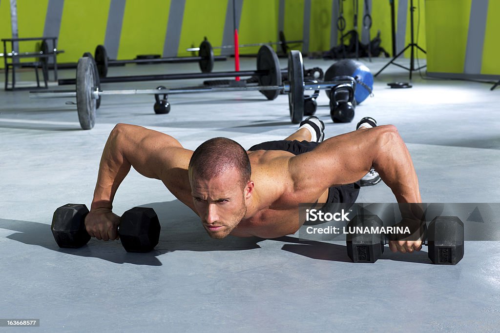 Muscular man doing pushups with dumbbells in gym Gym man push-up strength pushup exercise with dumbbell in a gym workout 20-29 Years Stock Photo