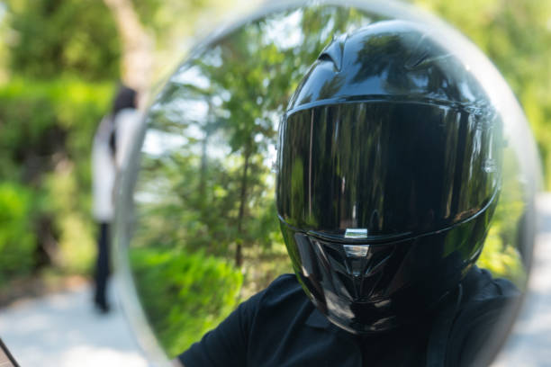 Helmet and tattooed biker riding motorcycle on forest road