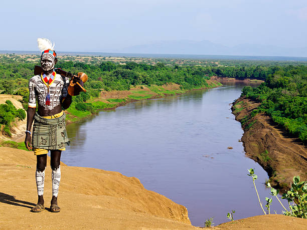 Karo warrior Traditional Karo tribe man with gun and wooden chair in his hand. In background is  Omo river and valley, South Ethiopia near border with Kenya, East Africa. omo river photos stock pictures, royalty-free photos & images