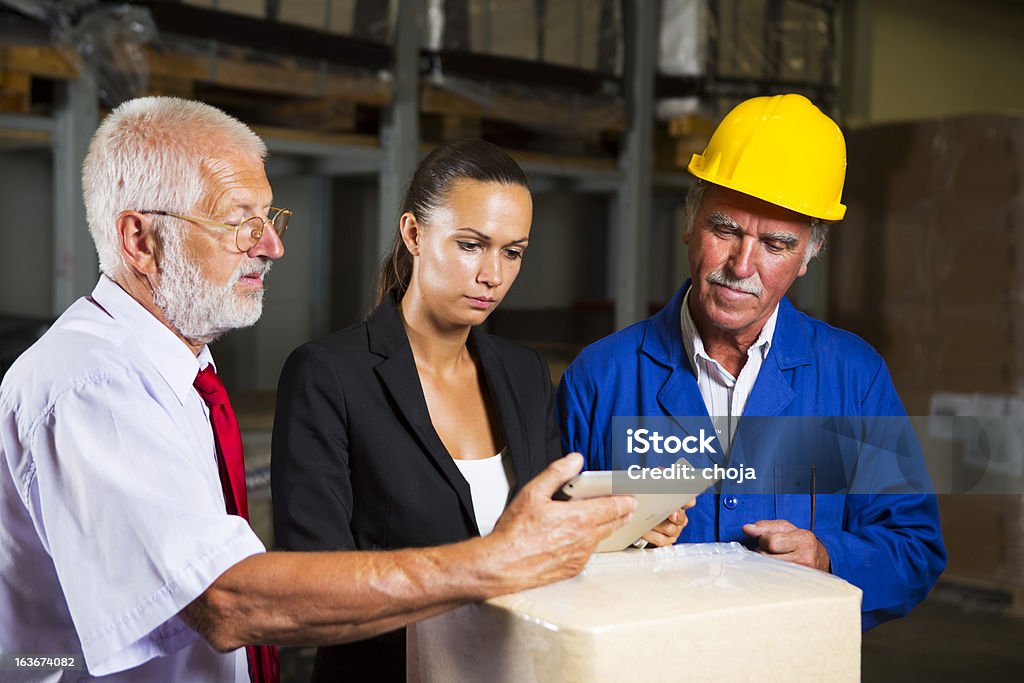 Linda inspector y dos trabajadores de almacén revisando suministros - Foto de stock de Accesorio de cabeza libre de derechos