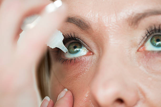 mujer usind eyedropper.applying gotas oftálmicas - seco fotografías e imágenes de stock