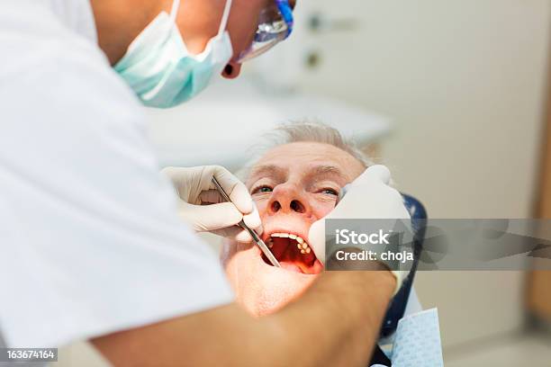 Senior Paciente Al Dentistdentist Es Extracting Los Dientes Foto de stock y más banco de imágenes de Alicates