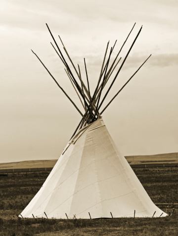 A majestic tipi sitting in the grasslands of an expansive prairie. Sepia toned and close-up.