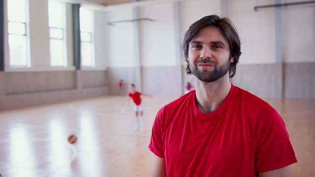 PE teacher standing indoors in gym class, physical education concept.