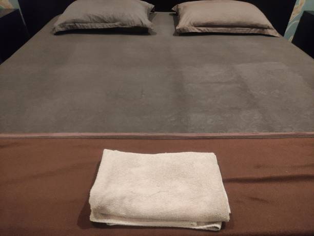 коричневая кровать с подушками и полотенцами, приготовленная в гостиничном номере - hotel pillow lodging bed стоковые фото и изображения