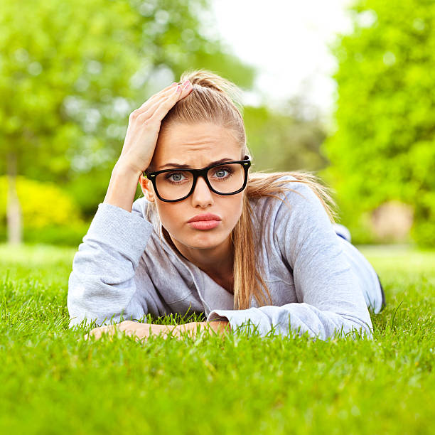 разочарованы девушка - glasses grass women lying on front стоковые фото и изображения