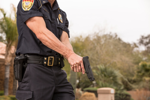 Policeman with his gun drawn. Arm Badge Create by me, Gold Chest Emblem Custom Ordered Generic. This stock image has a horizontal and outdoor composition.