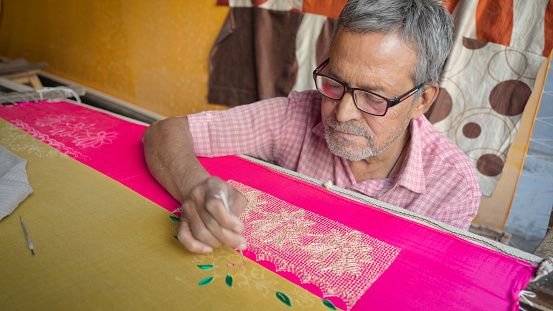 Indian man embroidering a scarf in Jaipur. Jaipur is known as the Pink City, because of the color of the stone exclusively used for the construction of all the structures.