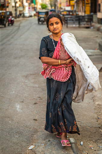 Young woman collecting plastic bottles from streets to sell it.