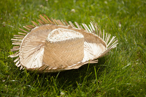 Farmer's yellow straw hat in the grass. Cowboy straw hat. Rural symbol.