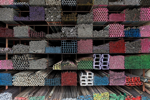 Various angle iron profiles and steel rods kept in storage shelves in a steel shop.