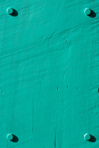 Turquoise grunge wood background with four bolts.