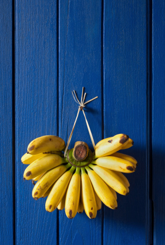 Market fresh bananas hanging on an old blue wooden wall.