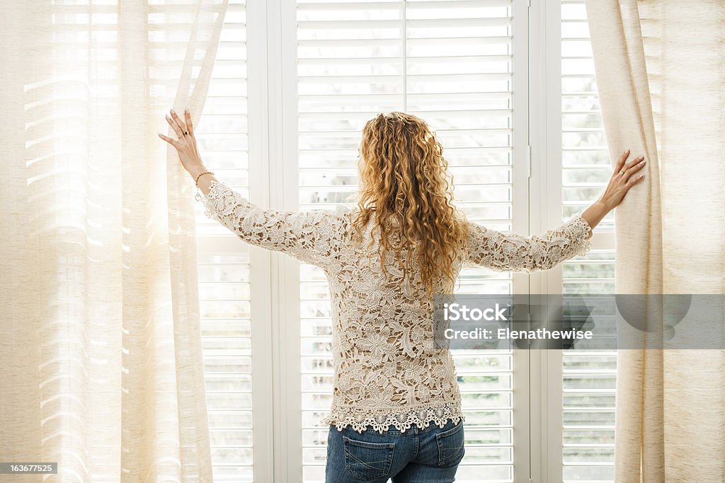 Donna guardando fuori la finestra - Foto stock royalty-free di Tapparella