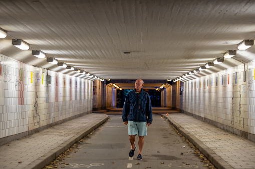 Stockholm, Sweden A man walks through a pedestrian and bicycle tunnel at night.