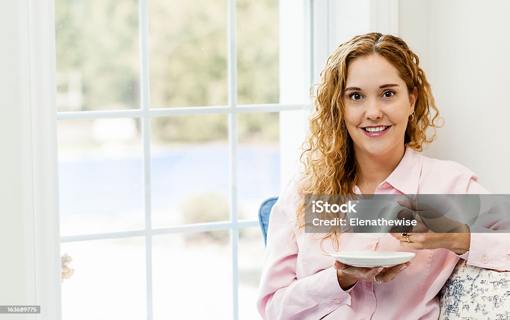 Donna rilassante vicino alla finestra con bevande - Foto stock royalty-free di Abbigliamento casual