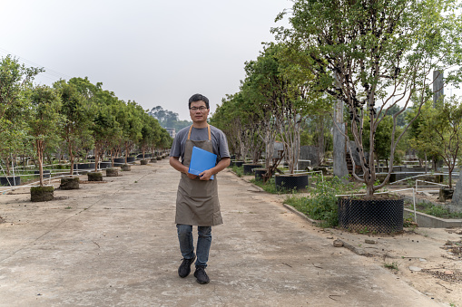 A male agricultural technician is recording data in the orchard