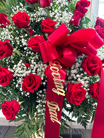 Red roses and baby’s breath with a “Loving Dad” ribbon at a funeral wake