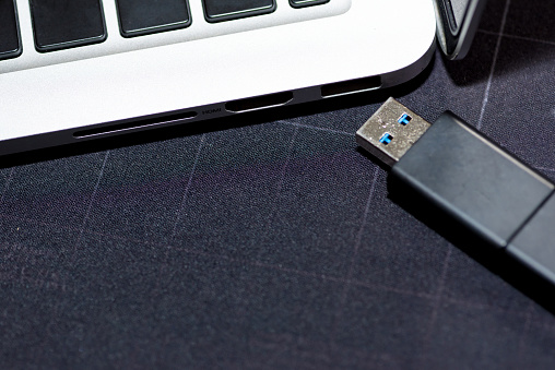 Hand inserting USB flash memory drive plugged into a computer laptop port.\n\nHand inserting Hardware Wallet plugged into a computer laptop.