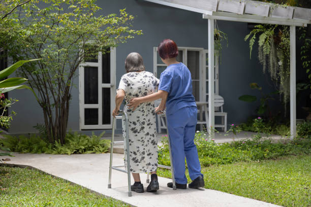istock Elderly woman exercise walking in backyard with caregiver. 1637139486