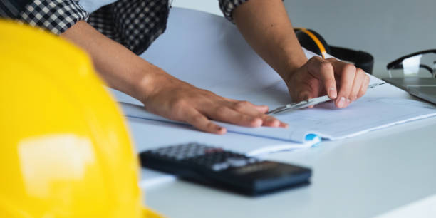 istock Closeup hand of engineer with construction work plan discussion together blueprint on working table in construction site with safety helmet 1637179508
