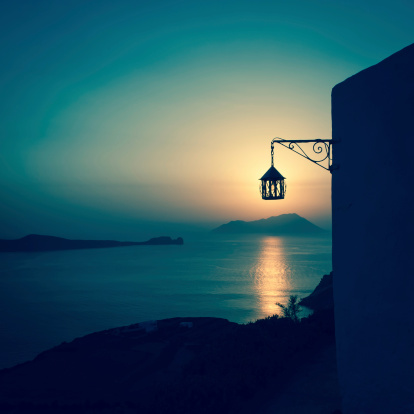 Sunset in Milos, Cyclades Islands, Greece. Focus on a classic lantern in the foreground.
