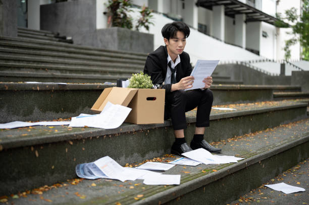 istock A stressed Asian businessman is reading his termination letter while sitting on the stairs 1637193702