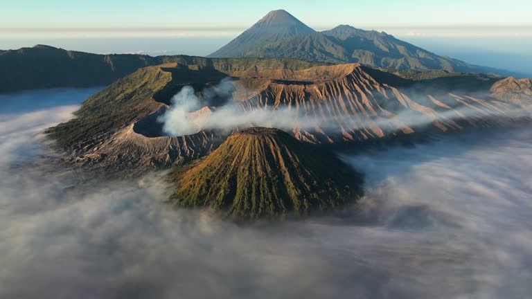 Aerial Drone Sunrise Scene of Eruption Volcano Mts. Bromo surrounded by Cloud, Fog and Smoke with mountain Semeru, Batok and Widodaren, Tengger Caldera,East Java, Java Island Indonesia