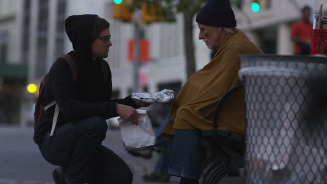 Young man shares food with homeless person