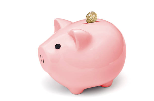 Isolated pink piggy bank with coins A British pound coins dropping into a pink piggy bank, isolated on white. piggy bank gold british currency pound symbol stock pictures, royalty-free photos & images