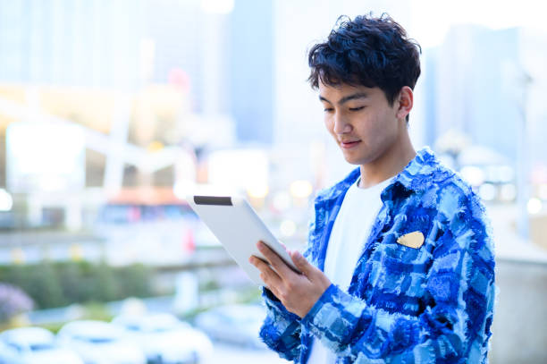 istock Asian young man using digital tablet in city street 1637254500
