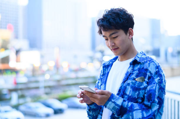 istock Asian young man using smartphone in city street 1637254507