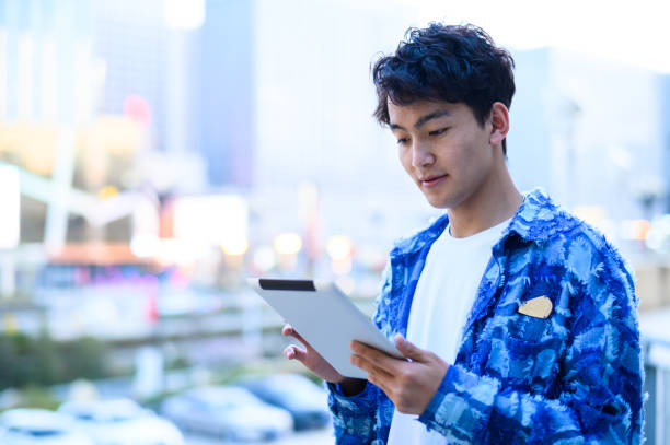 istock Asian young man using digital tablet in city street 1637254509