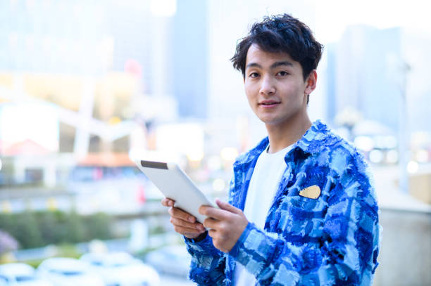 istock Asian young man using digital tablet in city street 1637254511