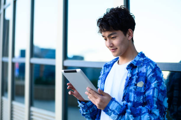 istock Asian young man using digital tablet in city street 1637254584
