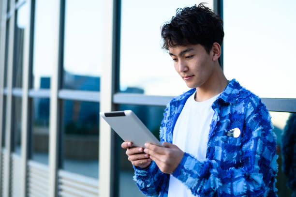 istock Asian young man using digital tablet in city street 1637254587