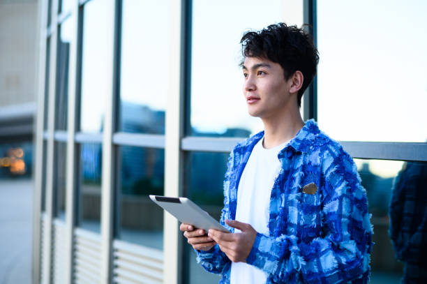 istock Asian young man using digital tablet in city street 1637254590