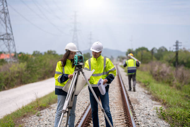 istock Surveyor engineers team wearing safety uniform,helmet and blueprint document checking inspection by theodolite to measurement position on railway construction site is industry transportation concept. 1637254880