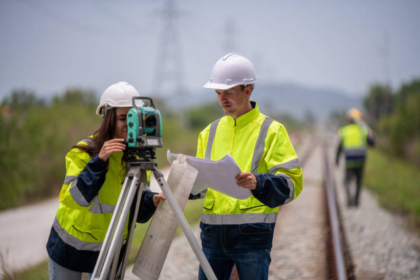 istock Surveyor engineers team wearing safety uniform,helmet and blueprint document checking inspection by theodolite to measurement position on railway construction site is industry transportation concept. 1637254897