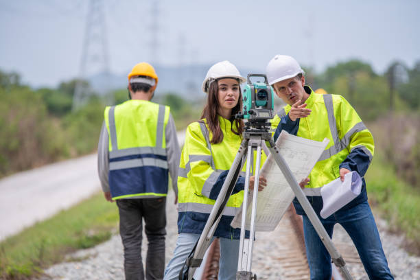 istock Surveyor engineers team wearing safety uniform,helmet and blueprint document checking inspection by theodolite to measurement position on railway construction site is industry transportation concept. 1637254903