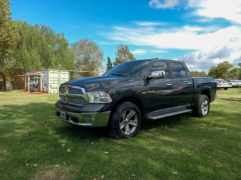 Chascomus, Argentina - Apr 15, 2023: Old black 2000s pickup truck Dodge Ram Hemi 5.7 Liter quad cab in the countryside. Nature, grass, trees. Classic car show