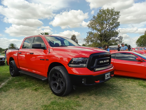 Chascomus, Argentina - Apr 15, 2023: Old red 2000s pickup truck Dodge Ram Hemi 5.7 Liter quad cab on the lawn. Nature, grass, trees. Classic car show