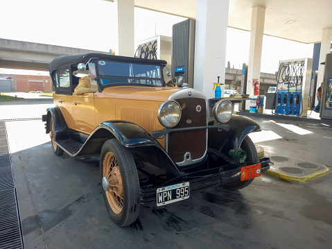 Chascomus, Argentina - Apr 15, 2023: Old vintage yellow Chrysler Plymouth phaeton circa 1930 in a gas station.
